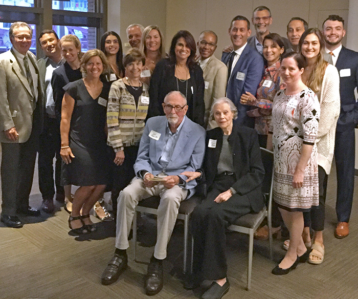 Milton Raben, MD, sits with his wife, surrounded by friends, family, former trainees and current faculty