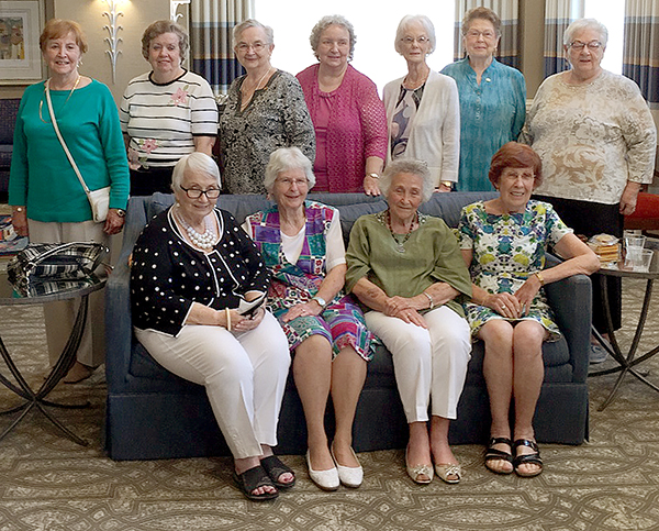 A group of older women pose seated and standing for a group photo