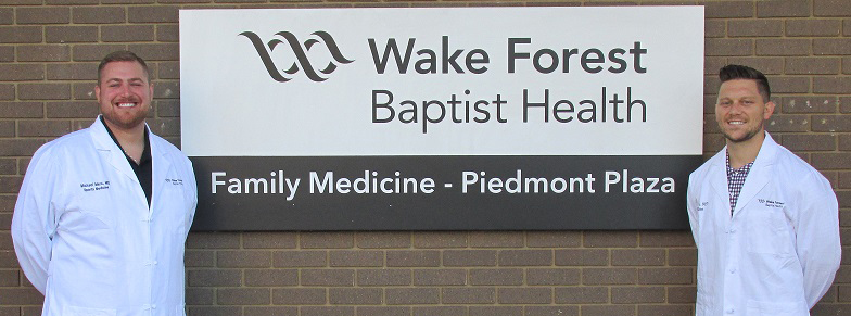 Primary Care Sports Medicine Fellows - Class of 2020 - Dr. Michael Merz and Dr. Matthew Horn stand in front of the sign for the Family Medicine clinic