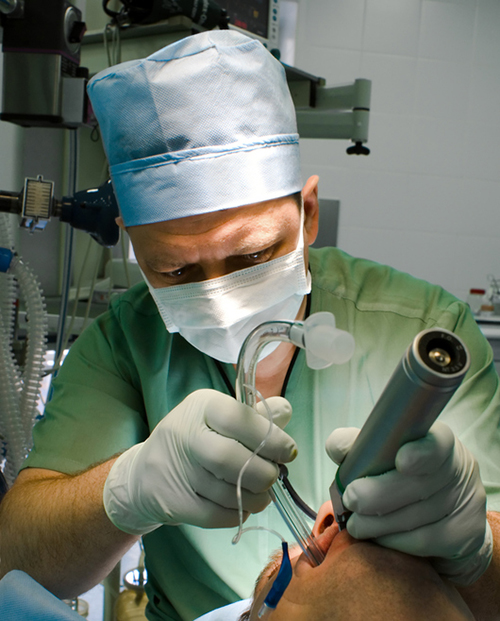 a man in green scrubs intubates a patient