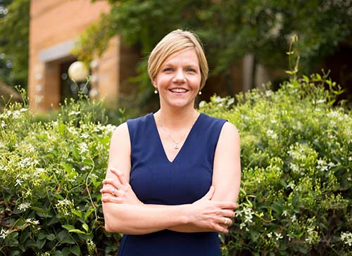 Ellen Murphy, Assistant Dean of Instructional Technologies and Design, stands outside in front of green hedge