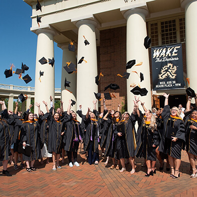 Graduating students celebrating together outside.
