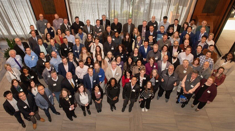 A group of students and faculty gather in a hallway for a group photo at the 2025 Research Symposium.
